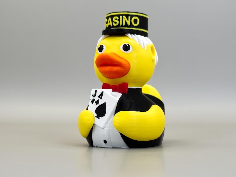 May include: A yellow rubber ducky wearing a black and white tuxedo, a red bow tie, and a black hat with "CASINO" printed on it. The duck holds a card with the Ace of Spades. A fun, novelty item.