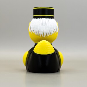 May include: A yellow figurine of a bellhop, viewed from the back. The figure has white hair, a black and yellow hat, and a black uniform with yellow accents. The design is a 3D print.