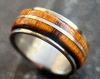 May include: A brown wood and stainless steel ring with two silver bands.