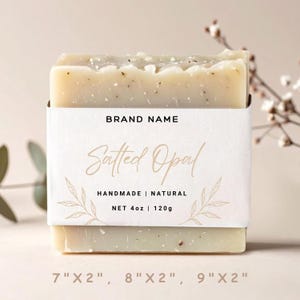 Puede incluir: Una pastilla de jabón artesanal y natural con el texto "Salted Opal" en una etiqueta blanca. La etiqueta también incluye "BRAND NAME", "HANDMADE | NATURAL" y "NET 4oz | 120g". El jabón mide aproximadamente 17.78cm x 5.08cm, 20.32cm x 5.08cm, o 22.86cm x 5.08cm.
