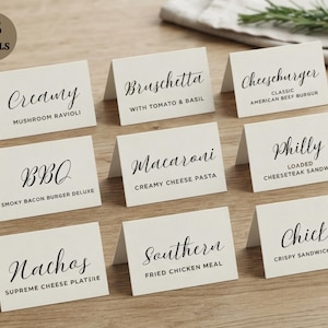 May include: A set of nine off-white folded paper food labels with black text. The labels feature various menu items including Creamy Mushroom Ravioli, Bruschetta, Cheeseburger, BBQ, Macaroni, Philly Cheesesteak, Nachos, Southern Fried Chicken, and Chicken.