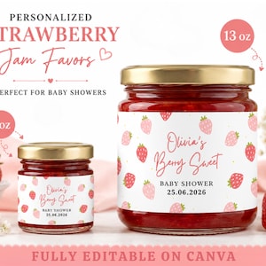 May include: Two glass jars of strawberry jam with gold lids, featuring white labels with a pink strawberry pattern and the text Olivia's Berry Sweet, Baby Shower, and 25.06.2026. The jars are labeled as 1 oz and 13 oz sizes respectively.