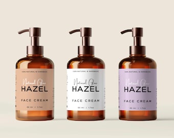 May include: Three amber-colored glass bottles with bronze-colored pump dispensers. Each bottle has a label that reads "Natural Glow HAZEL FACE CREAM" and "50 ml / 1.7 oz". The labels are in different colors: beige, white, and lavender.