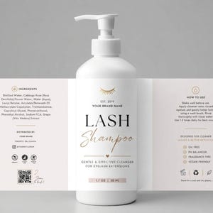 Op de afbeelding: Een witte plastic pompfles met wimper-shampoo en een etiket met gouden tekst en afbeeldingen. Het etiket vermeldt ingrediënten, gebruiksinstructies en productvoordelen zoals olievrij, pH-gebalanceerd, geurvrij en veganistisch, 50 ml.