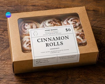 May include: A rectangular brown cardboard box with a clear window containing six cinnamon rolls topped with white icing. A white label on the front reads HOME BAKERY, CINNAMON ROLLS, ingredients, and net weight 7 oz (200 g) with a date of 12/08/2026.