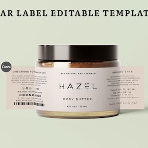 Peut inclure: Un pot de beurre corporel avec un couvercle noir et une étiquette rose pâle portant le texte HAZEL BODY BUTTER, 100% NATURAL AND HANDMADE, NET 6OZ | 200ML, ainsi que des instructions, des ingrédients et un code-barres.