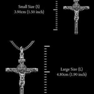 Puede incluir: Dos colgantes de crucifijo plateados, uno peque&ntilde;o (3,90 cm) y otro grande (4,80 cm), sobre un fondo negro. Cada colgante presenta a Jes&uacute;s en la cruz, con la inscripci&oacute;n INRI. Los colgantes est&aacute;n en una cadena.