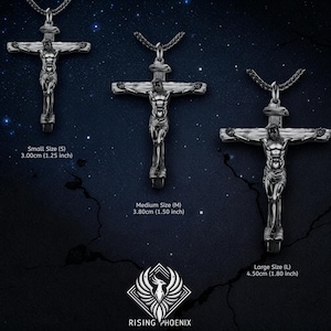 May include: Three silver-toned crucifix pendants of varying sizes are displayed against a dark blue background with stars. The sizes are labeled: Small (1.25 inches), Medium (1.50 inches), and Large (1.80 inches). The Rising Phoenix logo is at the bottom.