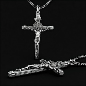 Puede incluir: Collar con colgante de cruz crucifijo plateado. La cruz presenta una representaci&oacute;n detallada de Jesucristo, con las letras INRI arriba. El colgante est&aacute; suspendido de una cadena plateada. La imagen muestra dos crucifijos, uno de pie y otro tumbado.