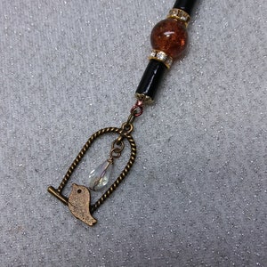 Pájaro en jaula/Tirador de cremallera/Cristal de Aurora Boreal/Cuentas negras y marrones/Espaciadores de pedrería/Encanto de bolso