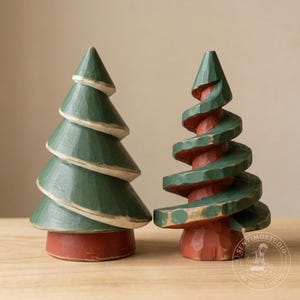 May include: Two hand-carved wooden tree figurines. The left tree is solid green with a red base and visible carved edges. The right tree features a spiral design with green branches and a red trunk. Both have a rustic finish with visible wood grain.