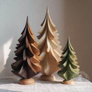 Può includere: Tre alberi decorativi in legno con rami intagliati a strati su basi circolari. Gli alberi sono rifiniti in tonalità marrone scuro, legno chiaro naturale e verde tenue. È visibile un logo circolare con il testo SENTIMOSTUDIO.