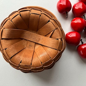 Op de afbeelding: Een bruine geweven mand met een handvat en de tekst "Longaberger Baskets" en "Dresden Ohio USA".