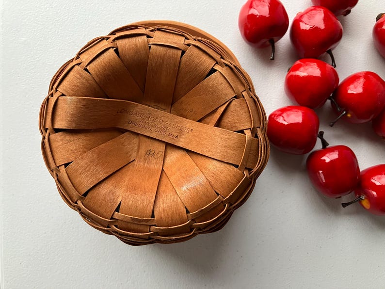 Op de afbeelding: Een bruine geweven mand met een handvat en de tekst "Longaberger Baskets" en "Dresden Ohio USA".