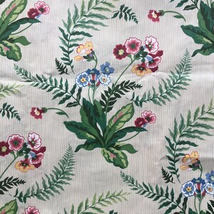 May include: A patterned fabric with a cream background and vertical stripes. The design showcases green fern leaves and clusters of red, yellow, and blue flowers. The repeating pattern creates a botanical theme, suitable for various textile applications.
