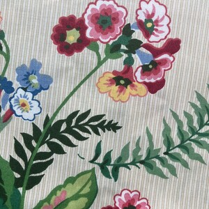 May include: Close-up of a floral pattern on cream fabric with vertical stripes. The design features clusters of red, pink, yellow, and blue flowers with green leaves. The fabric has a vintage aesthetic.