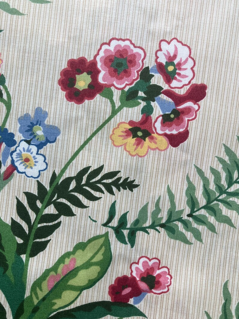 May include: Close-up of a floral pattern on cream fabric with vertical stripes. The design features clusters of red, pink, yellow, and blue flowers with green leaves. The fabric has a vintage aesthetic.