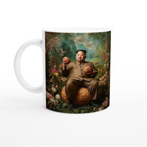 以下が含まれることがあります： 庭園の風景の中で、大きな茶色の球体に座っている男性のカラフルな画像が描かれた白いセラミック製のマグカップ。男性は茶色のスーツを着て、両手に茶色の球体を2つ持っています。