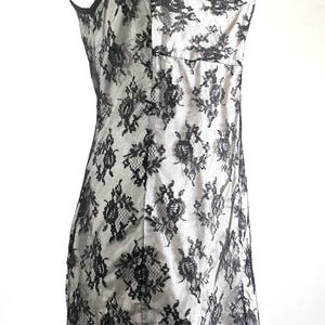 May include: A white ceramic mug with a black handle and the text "But First, Coffee" in a bold, black font. The mug is set against a blurred background, suggesting a cozy setting.