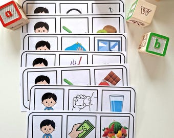 Könnte beinhalten: Lernkarten mit Cartoon-Illustrationen und deutschen Wörtern. Die Karten zeigen Bilder eines Jungen, eines grünen Stifts, einer Kiwi, eines Fensters, einer Schokoladentafel, eines Wasserglases und Obst. Holzbuchstabenwürfel sind verstreut.