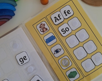 Könnte beinhalten: Ein Lernspielset mit Wort- und Bildkarten, darunter ein Affe und ein Sofa. Zusätzliche Wortkacheln und Holzpuppen in verschiedenen Farben sind ebenfalls vorhanden. Ein Regenbogen-Holzbogen ist sichtbar.