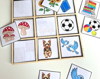 Könnte beinhalten: Ein hölzernes Tic-Tac-Toe-Spielbrett mit illustrierten Karten mit einem Fußball, Sonnenblumen, einem Pilz, einem blauen Vogel, einem Buch und einem Yorkshire Terrier. Zusätzliche Karten zeigen ein Auto, einen Tennisball und einen Stapel Bücher.