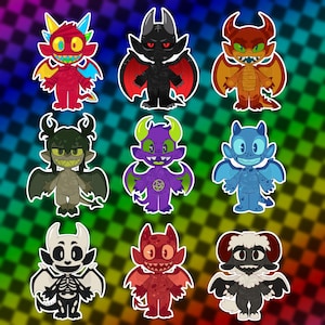 May include: A collection of nine cartoon monster stickers featuring diverse designs including a red multi-colored creature, a black winged demon, an orange dragon, a dark green imp, a purple creature with a pentagram, a blue spotted monster, a skeleton demon, a red spotted monster, and a black sheep-like creature.
