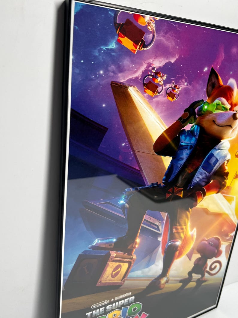 May include: Framed poster featuring a cartoon fox character in a futuristic setting with a space background. The fox is wearing a blue jacket and green goggles. A small monkey-like creature is also present. The poster has the text "The Super Mario Bros. Movie".