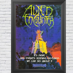 May include: A framed poster with a colorful illustration of a futuristic tower with the text "Alien Encounter" in a stylized font. The text below the image reads "It's here and there's nothing on earth we can do about it." The poster is framed in black.
