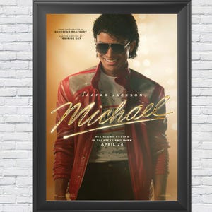 Puede incluir: Póster enmarcado de la película "Michael" con Jaafar Jackson. El póster tiene una paleta de colores cálidos con una chaqueta roja y letras doradas. El texto dice "His story begins in theaters and IMAX April 24."