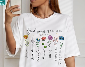 May include: White t-shirt with a floral design and the text "God says you are" with words describing each flower: Unique, Special, Lovely, Precious, Strong, Chosen, Forgiven.