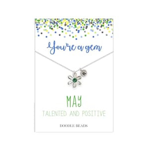 May include: A silver necklace with a green gemstone flower charm and a silver initial charm. The card reads "You're a gem May Talented and Positive Doodle Beads".