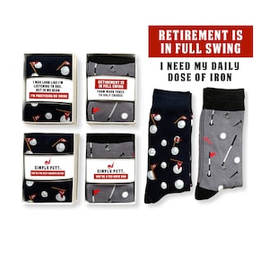 May include: Four gift boxes with golf-themed socks and sayings. The boxes are white with black and red accents. The socks are blue and gray with white golf balls and red flags. The sayings on the boxes include "I may look like I'm listening to you, but in my head I'm practicing my swing", "Retirement is in full swing from work force to golf course", "Simply putt. You're the best grandpa on par", and "Simply putt. You're a tee-rific dad".