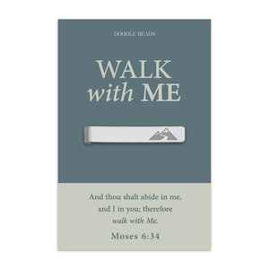 May include: A silver-colored tie clip with a mountain range design, displayed on a card with the text "WALK with ME". The card also includes the text "And thou shalt abide in me, and I in you; therefore walk with Me. Moses 6:34."