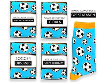 以下が含まれることがあります： サッカーをテーマにした靴下。水色の靴下に白と黒のサッカーボールの模様。4足は白い箱に入っており、「Practice with a Purpose」、「What's Life Without Goals」、「Soccer Obsessed」、「Kick Up Some Fun Happy Birthday」と書かれています。オレンジ色の袖口が付いた靴下も1足あります。