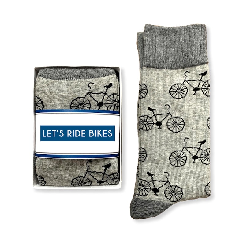 May include: A pair of gray socks with a black bicycle pattern. The socks are packaged in a white box with a blue and white label that reads "LET'S RIDE BIKES".