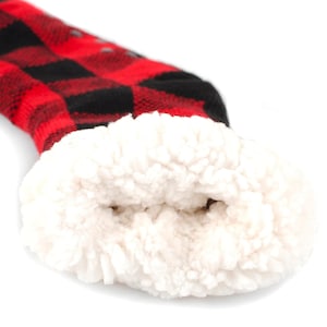 May include: Red and black plaid slipper socks with a white sherpa lining. The socks are turned inside out to show the lining.