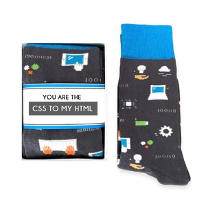 May include: A pair of black socks with a blue cuff, featuring a fun pattern of computer-related icons and the text "You are the CSS to my HTML". The socks are packaged in a white box.