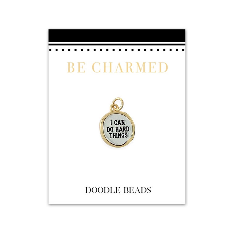 May include: Gold charm with the text "I can do hard things" on a white background. The charm is on a white card with the text "Be Charmed" and "Doodle Beads".