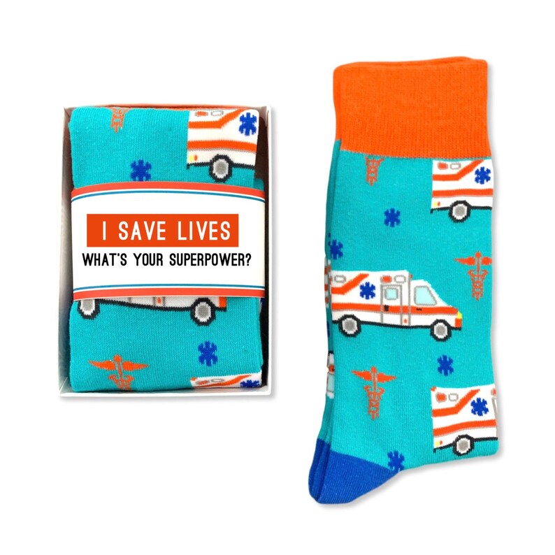 May include: A pair of blue socks with a white ambulance and red cross pattern. The socks come in a white box with the text "I save lives. What's your superpower?"