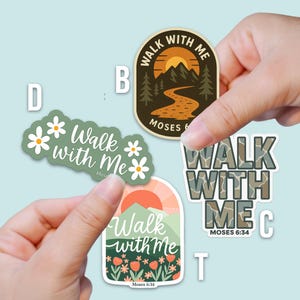 May include: Four stickers with the text "Walk with Me" and "Moses 6:34". Designs include a mountain scene, daisies, and a camouflage pattern. The stickers are held by hands against a light blue background.