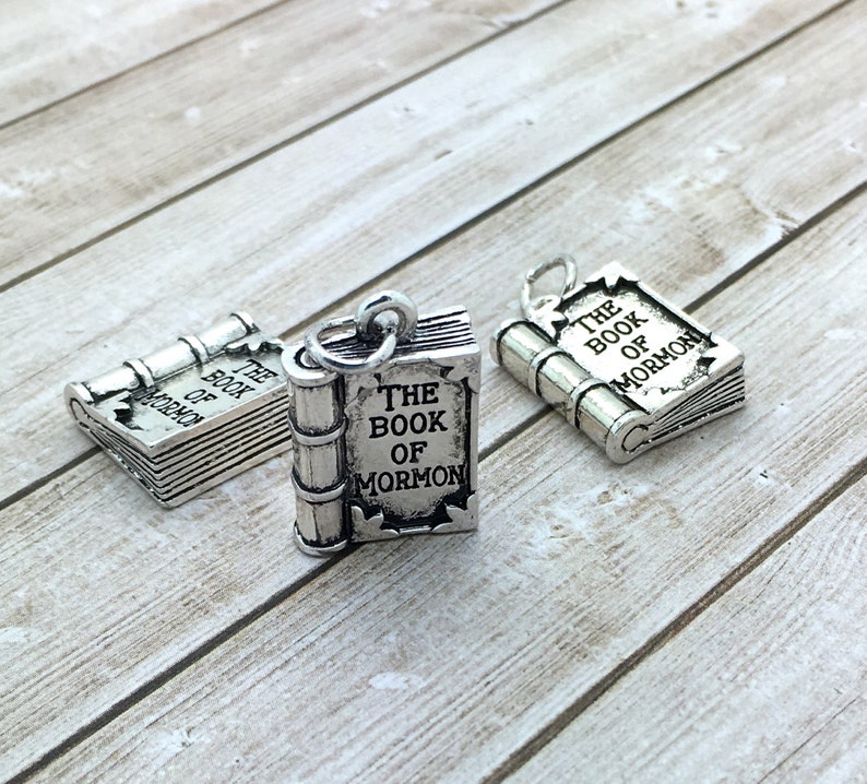 May include: Three silver charm pendants shaped like closed books with the words "The Book of Mormon" engraved on the front.