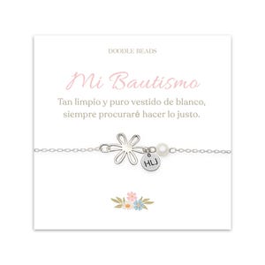 May include: A silver bracelet with a flower charm, a pearl, and a small round charm with the initials "HLJ". The bracelet is on a white card with the text "Mi Bautismo" and a Spanish quote.