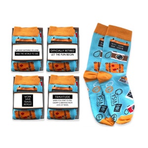 以下が含まれることがあります： 旅行をテーマにしたデザインとことわざが書かれた靴下の箱が4つあります。箱はオレンジとブルーで、スーツケースと飛行機のグラフィックが描かれています。箱に書かれたことわざは、「失うものは何もない、そして世界を見る」「正式に引退しました。楽しみを始めましょう」「働き、貯め、旅をし、繰り返す」「トラビチュード。旅行不足で不機嫌になり、イライラし始めるとき」です。箱の隣には、旅行をテーマにした青い靴下1足が置かれています。靴下には、スーツケース、飛行機、カメラ、パスポート、ビザのグラフィックが描かれています。