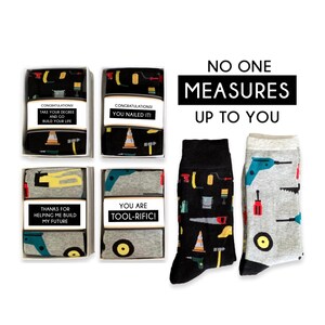 May include: Four gift boxes with different tool-themed designs and messages. The boxes contain socks with a black and grey background and colorful tool illustrations. The text on the boxes reads: "Congratulations! Take your degree and go build your life", "Congratulations! You nailed it!", "Thanks for helping me build my future", and "You are tool-rific!". The text above the boxes reads: "No one measures up to you."