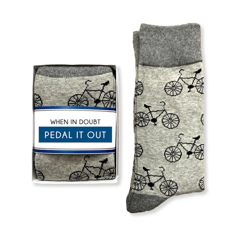 May include: A pair of gray socks with a black bicycle pattern. The socks come in a box with the text "When in doubt, pedal it out".