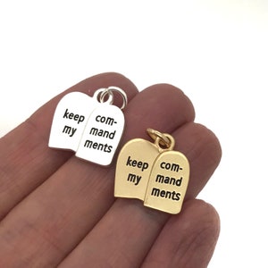 May include: Two silver and gold charms shaped like stone tablets with the words "keep my commandments" engraved on them.