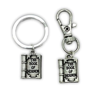 May include: Two silver keychains with a book charm. The charms feature the text "The Book of Mormon".