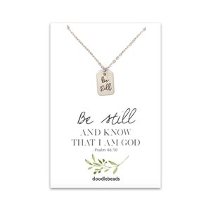 Dainty "Be Still" necklace charm- small rectangle shaped flat disc  with be still engraved on it set on a silver or gold adjustable chain.  it is paired with a card that says be still and know that I am God