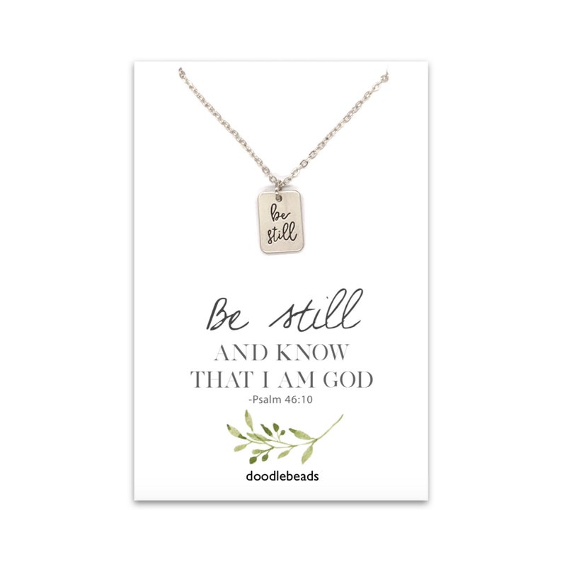 Dainty "Be Still" necklace charm- small rectangle shaped flat disc  with be still engraved on it set on a silver or gold adjustable chain.  it is paired with a card that says be still and know that I am God